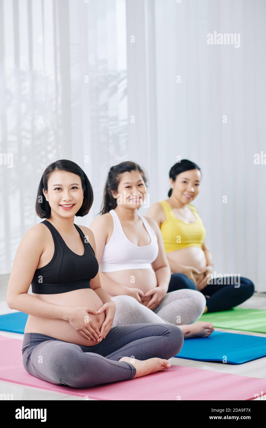 Happy smiling young Asian women sitting on yoga mat in sports class and ...