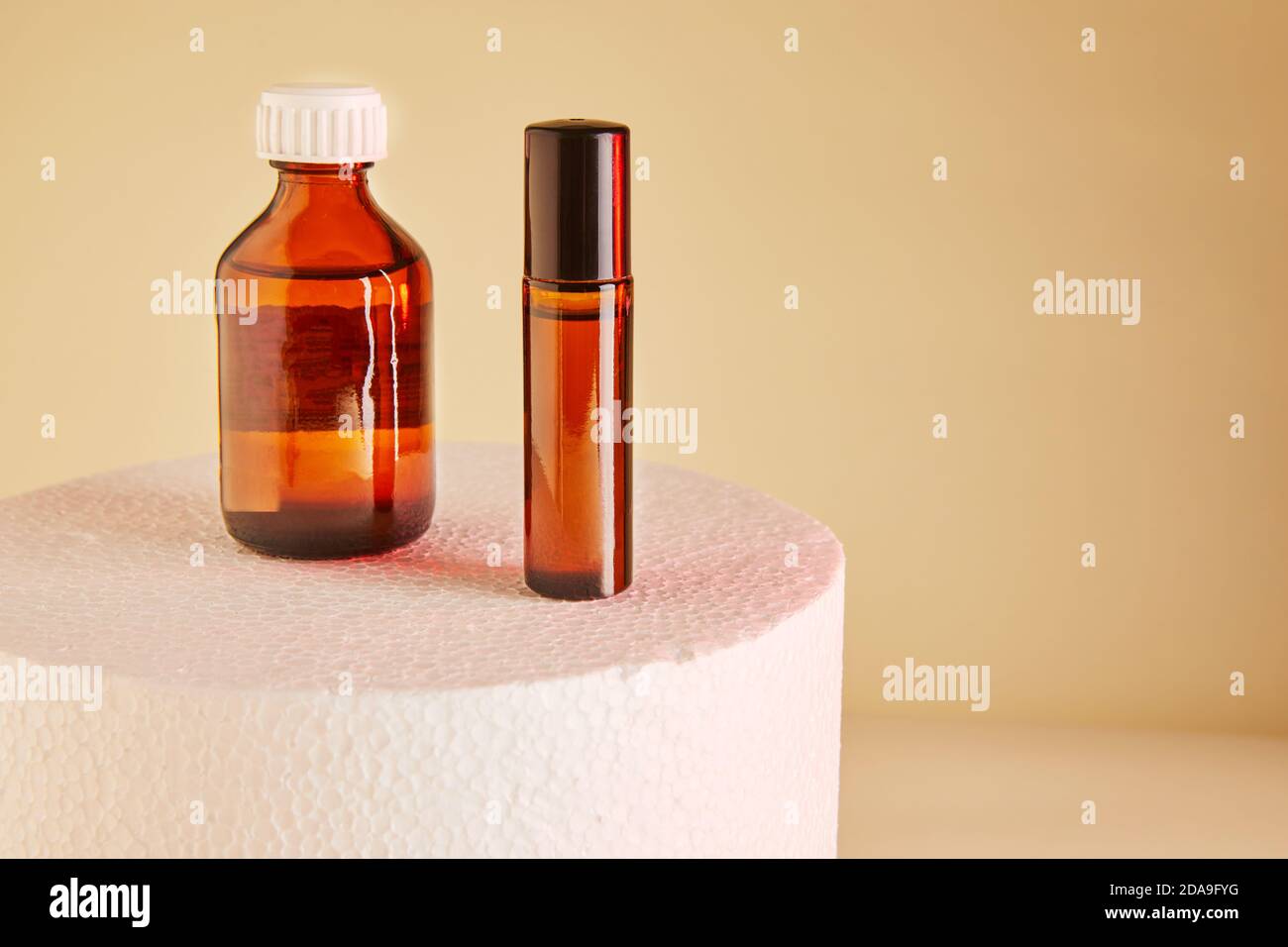 Dropper Bottle - Amber Glass of perfume, shower gel, unlabeled bottles on white podium. Stock Photo