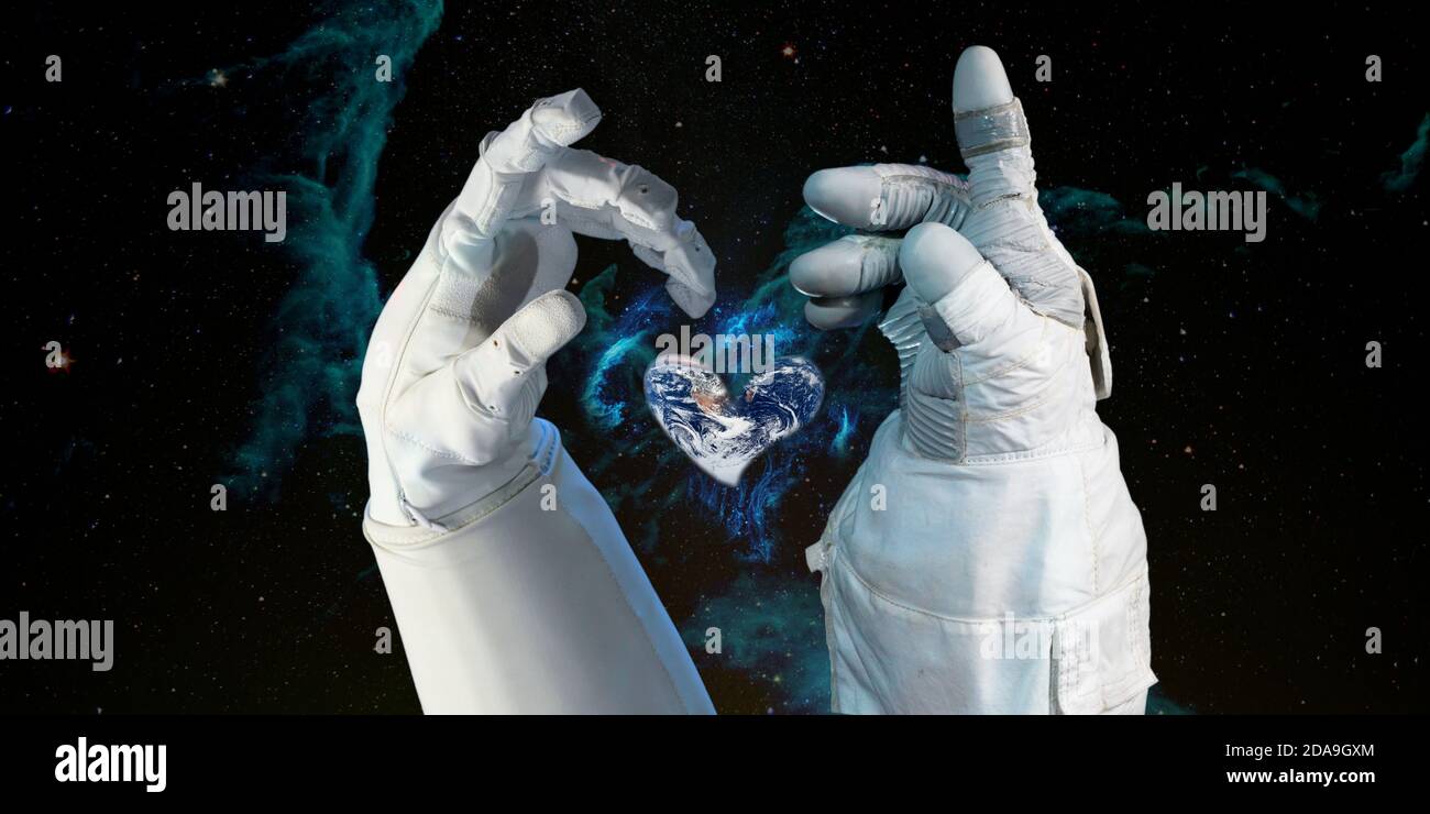 Earth heart in astronaut hands in space background, among stars and galaxies, World environment day and give love to our world concept. Elements of th Stock Photo