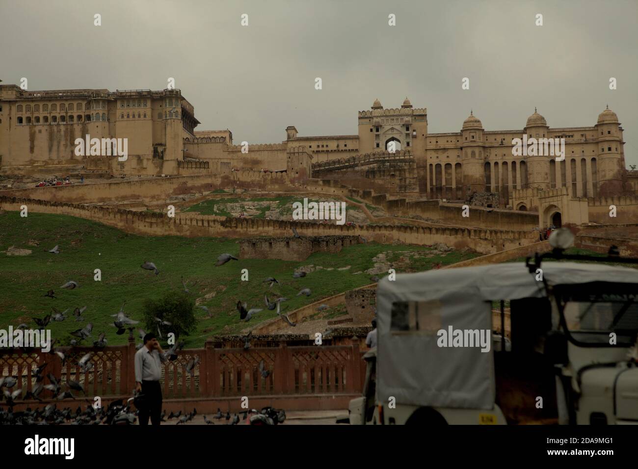 A view of Amer Fort and a roadside where people, doves and an auto ...