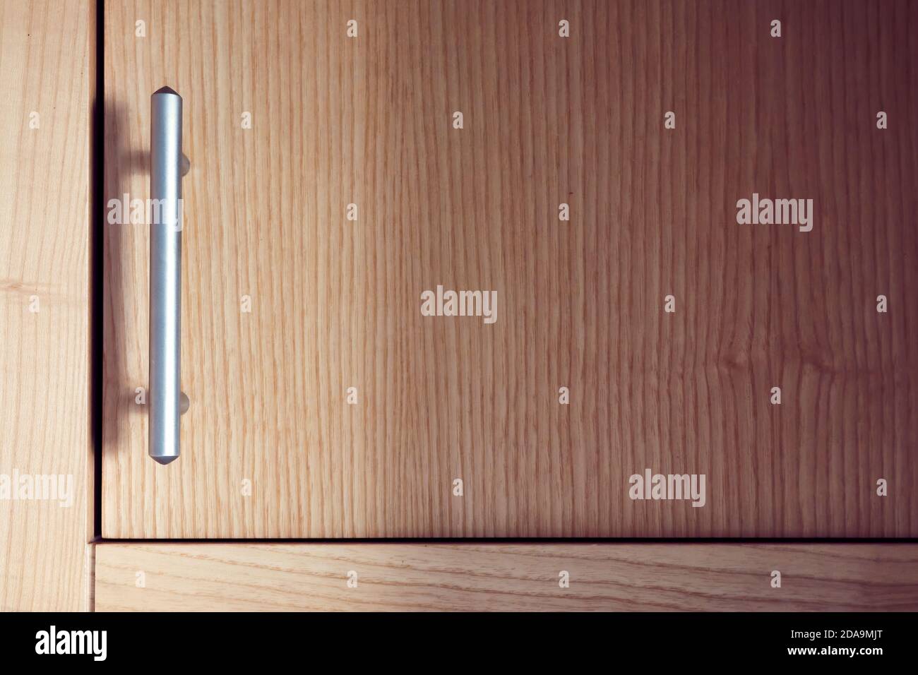Satin nickel plated door handle on an alder wood cupboard or