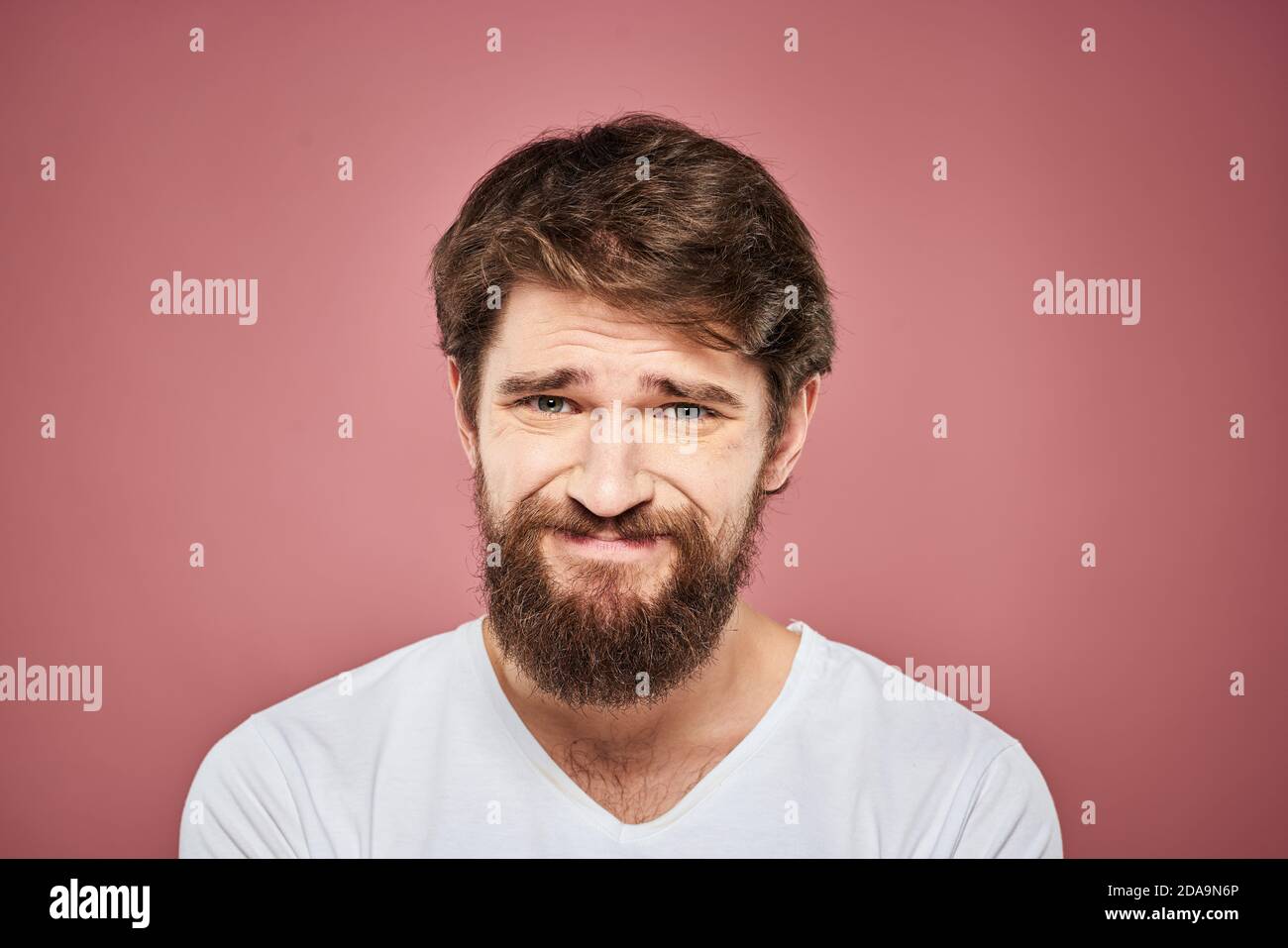 Emotional bearded man in white T-shirt discontent pink background Stock ...