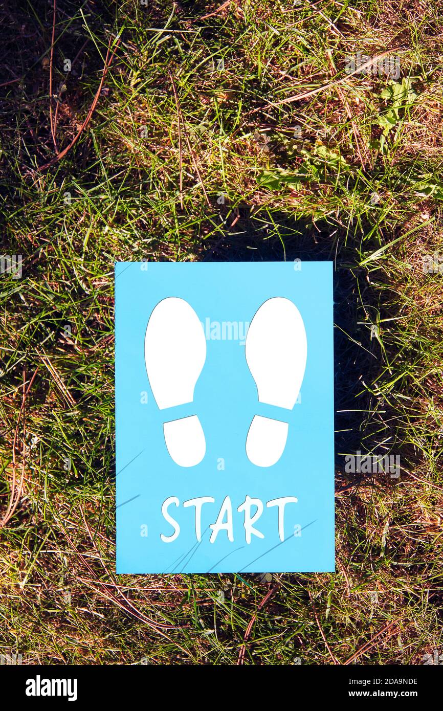 The word start written on blue paper with footprint on green grass ...