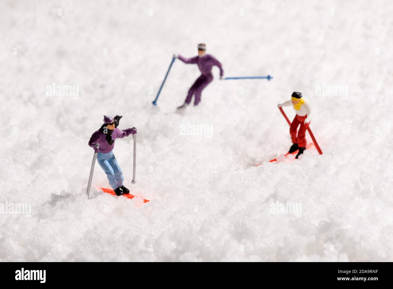 Three miniature people skiing in fresh white winter snow traversing the slope in a travel and vacation concept Stock Photo