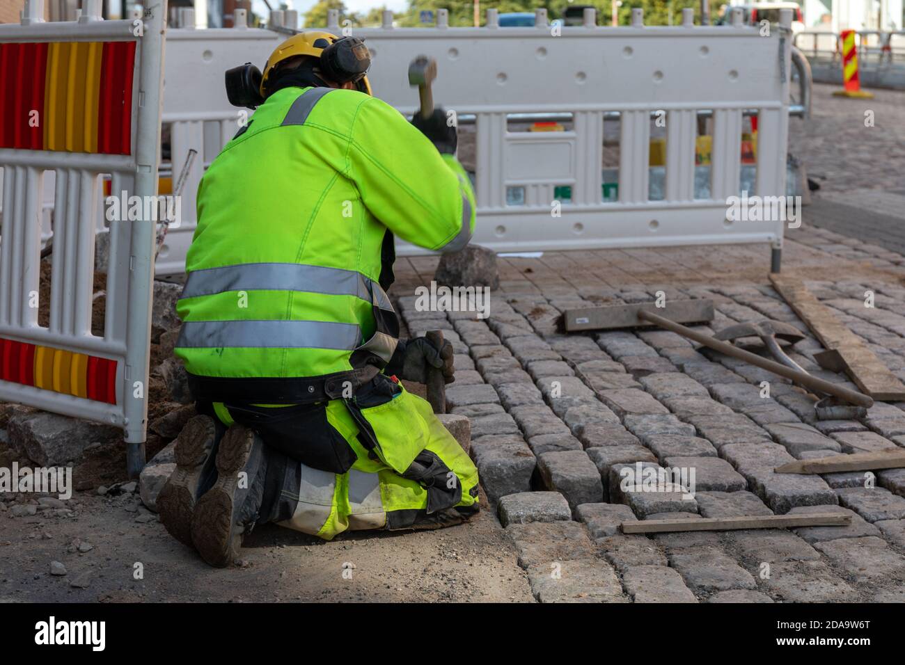 Man laying setts or blocks on Viides Linja in Kallio district of Helsinki, Finland Stock Photo