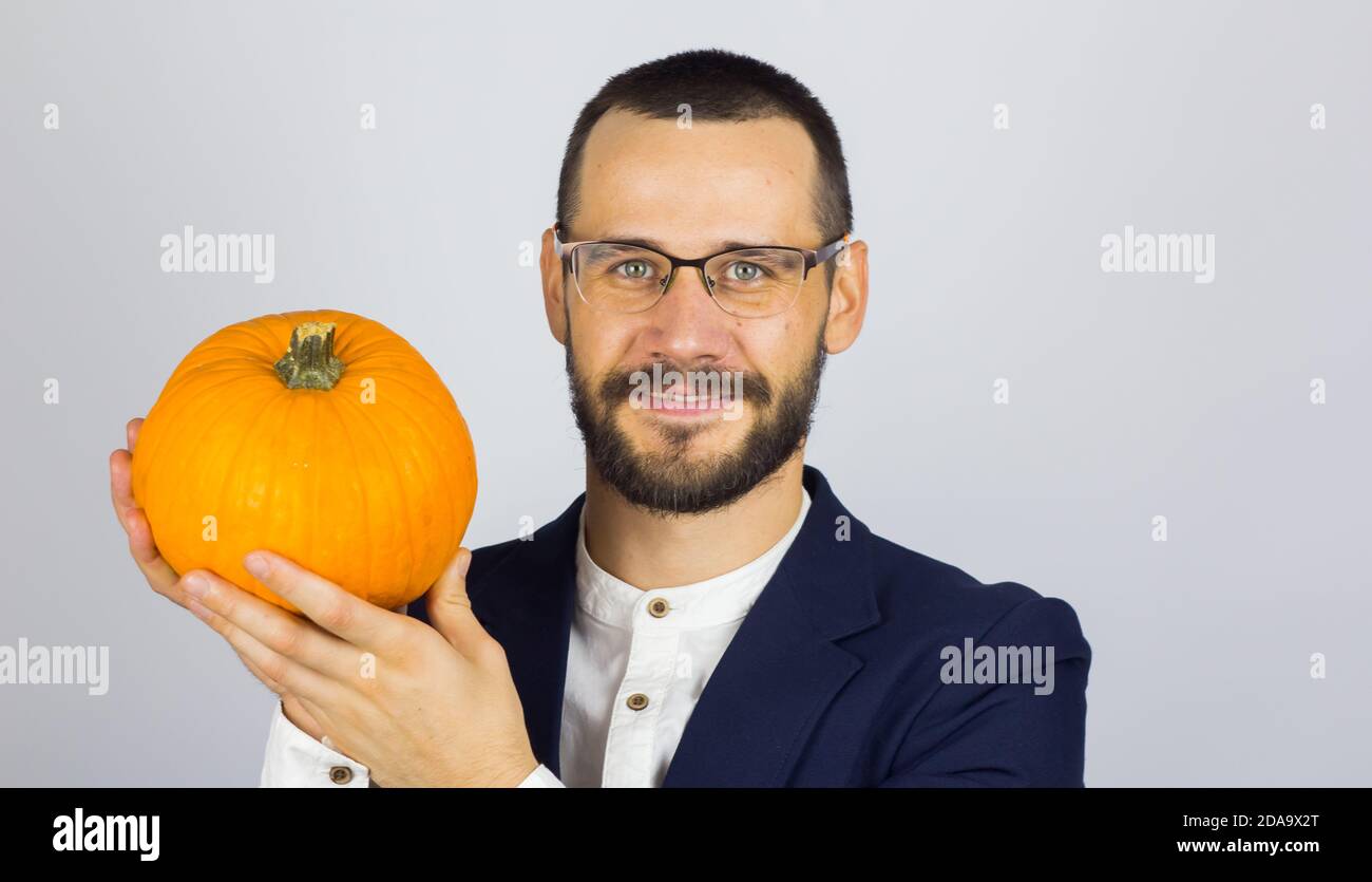 A young handsome businessman is holding a pumpkin in his hands and getting ready for the halloween celebration. Stock Photo