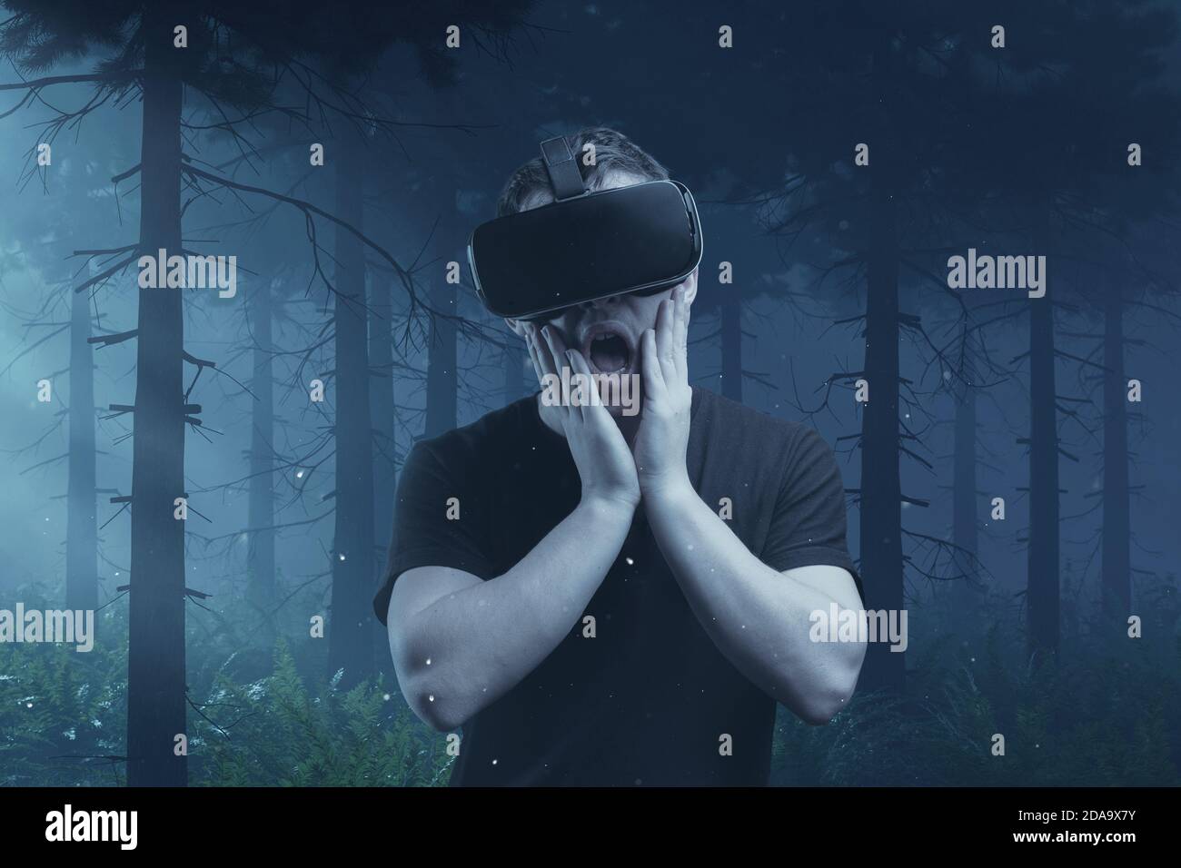 scary young man getting experience with vr device playing horror game in front of foggy forest Stock Photo