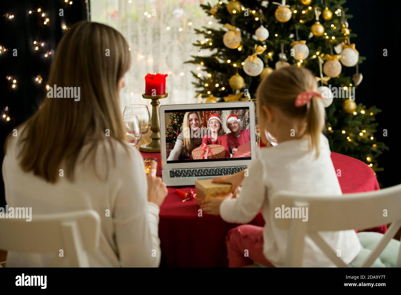 A happy family with a child is celebrating Christmas with their friends on video call using webcam. Family greeting their relatives on Christmas eve Stock Photo