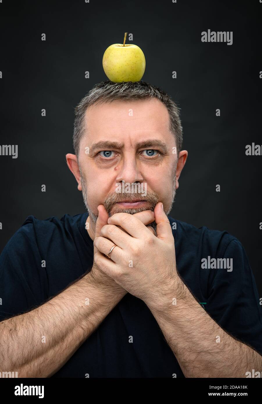 Portrait of a middle-aged man with a green apple on his head Stock Photo