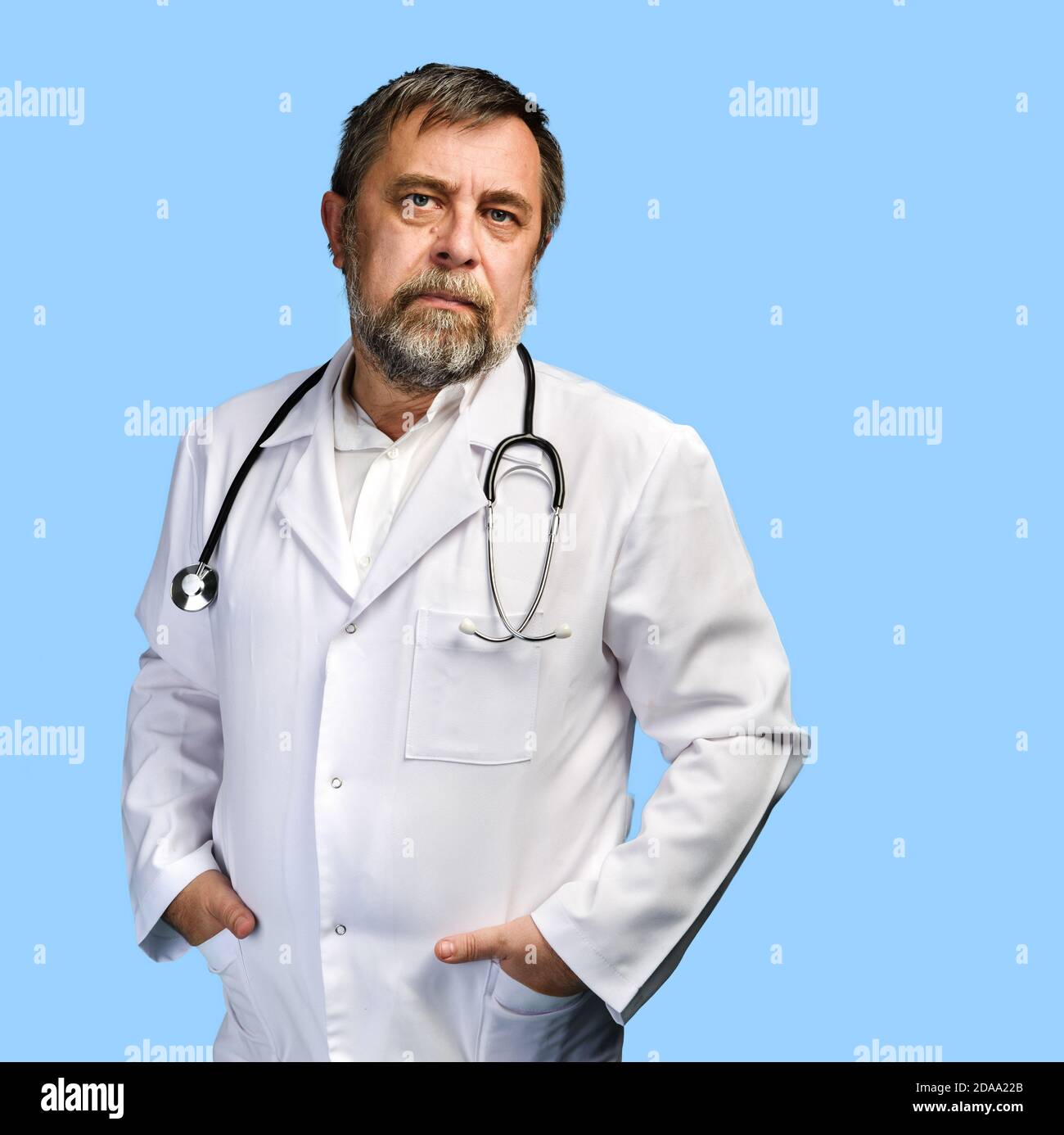 Portrait of handsome tired medical doctor with stethoscope in white coat isolated on blue background with copyspace Stock Photo