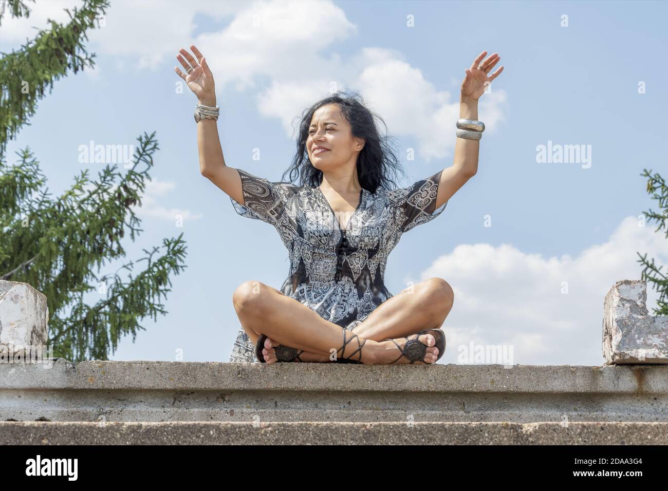 Young brunette girl sitting in lotus position on a background of blue ...