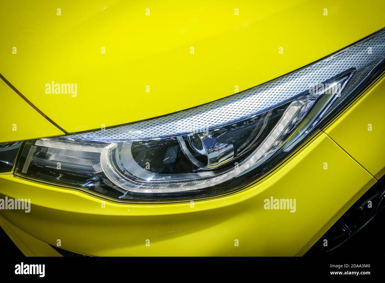 Close-up LED xenon headlight of yellow modern car with halogen lamp technology for illuminate both day and night. Stock Photo