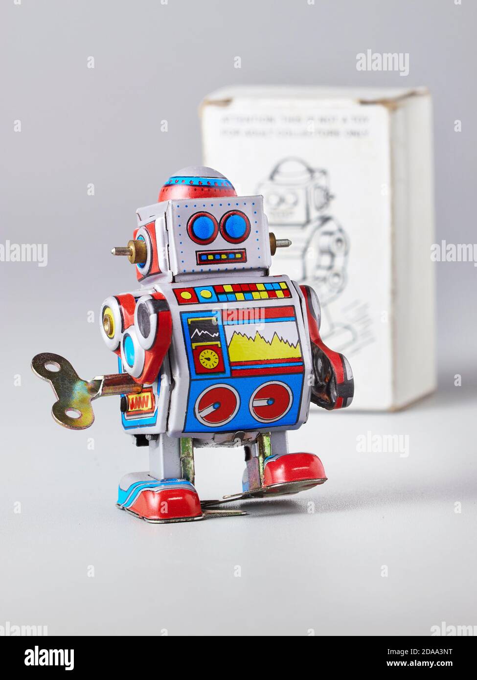 The tin toy robot is walking against the background of the cardboard packaging Stock Photo