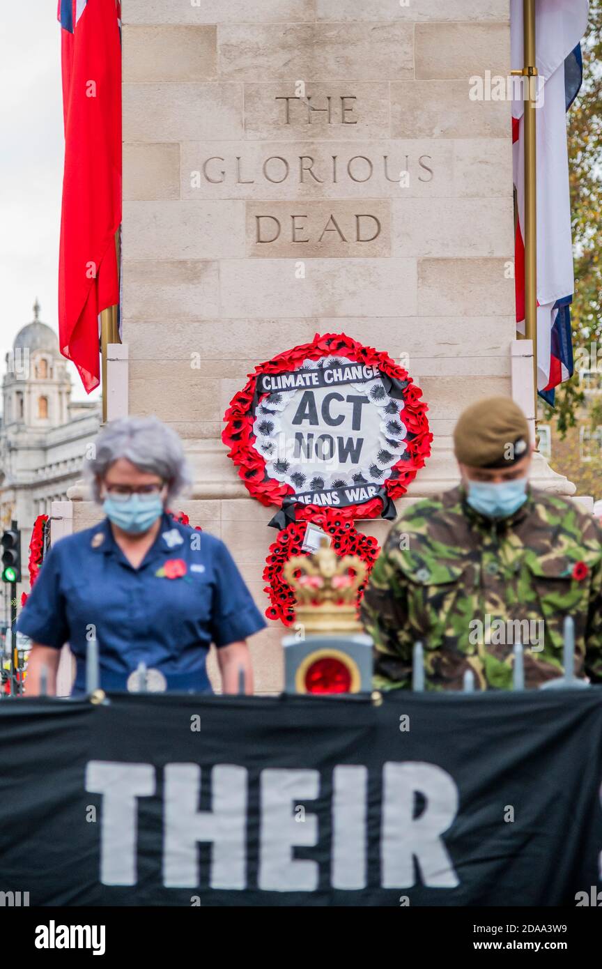 London, UK. 11th Nov, 2020. ‘Honour Their Sacrifice': Extinction Rebellion Veteran and a Nurse Pay Respects at the Cenotaph with Banner Warning Climate Change Means War. The action comes as an MoD commissioned report published in June this year warns of the “growing recognition that climate change may aggravate existing threats to international peace and security.” Extinction Rebellion protest at the Cenotaph about the risk of future conflict resulting from climate change. Credit: Guy Bell/Alamy Live News Stock Photo