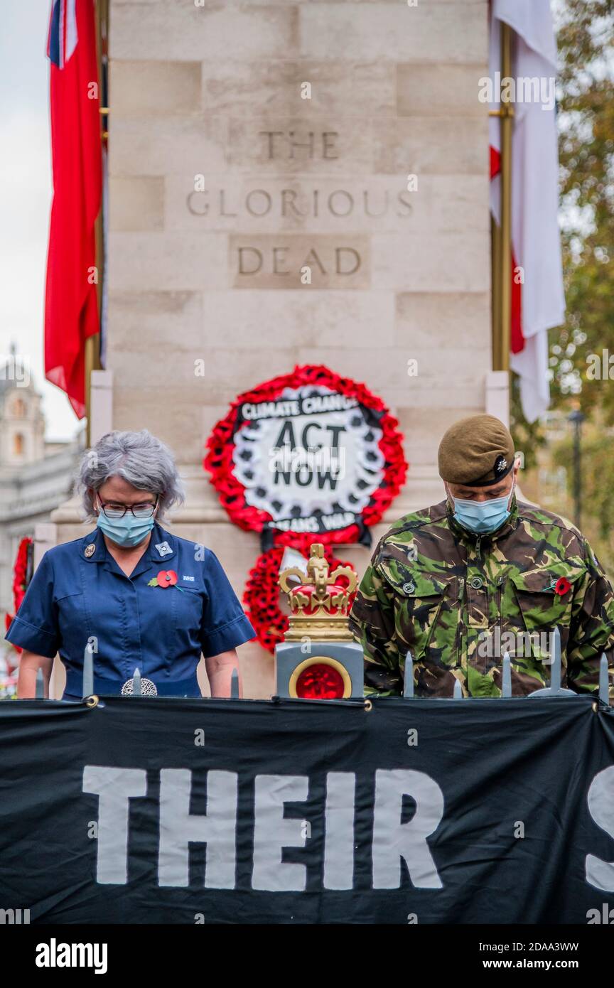 London, UK. 11th Nov, 2020. ‘Honour Their Sacrifice': Extinction Rebellion Veteran and a Nurse Pay Respects at the Cenotaph with Banner Warning Climate Change Means War. The action comes as an MoD commissioned report published in June this year warns of the “growing recognition that climate change may aggravate existing threats to international peace and security.” Extinction Rebellion protest at the Cenotaph about the risk of future conflict resulting from climate change. Credit: Guy Bell/Alamy Live News Stock Photo