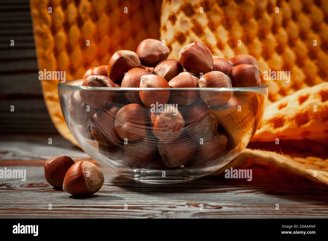 hazelnuts in a glass cup on a yellow textile background Stock Photo