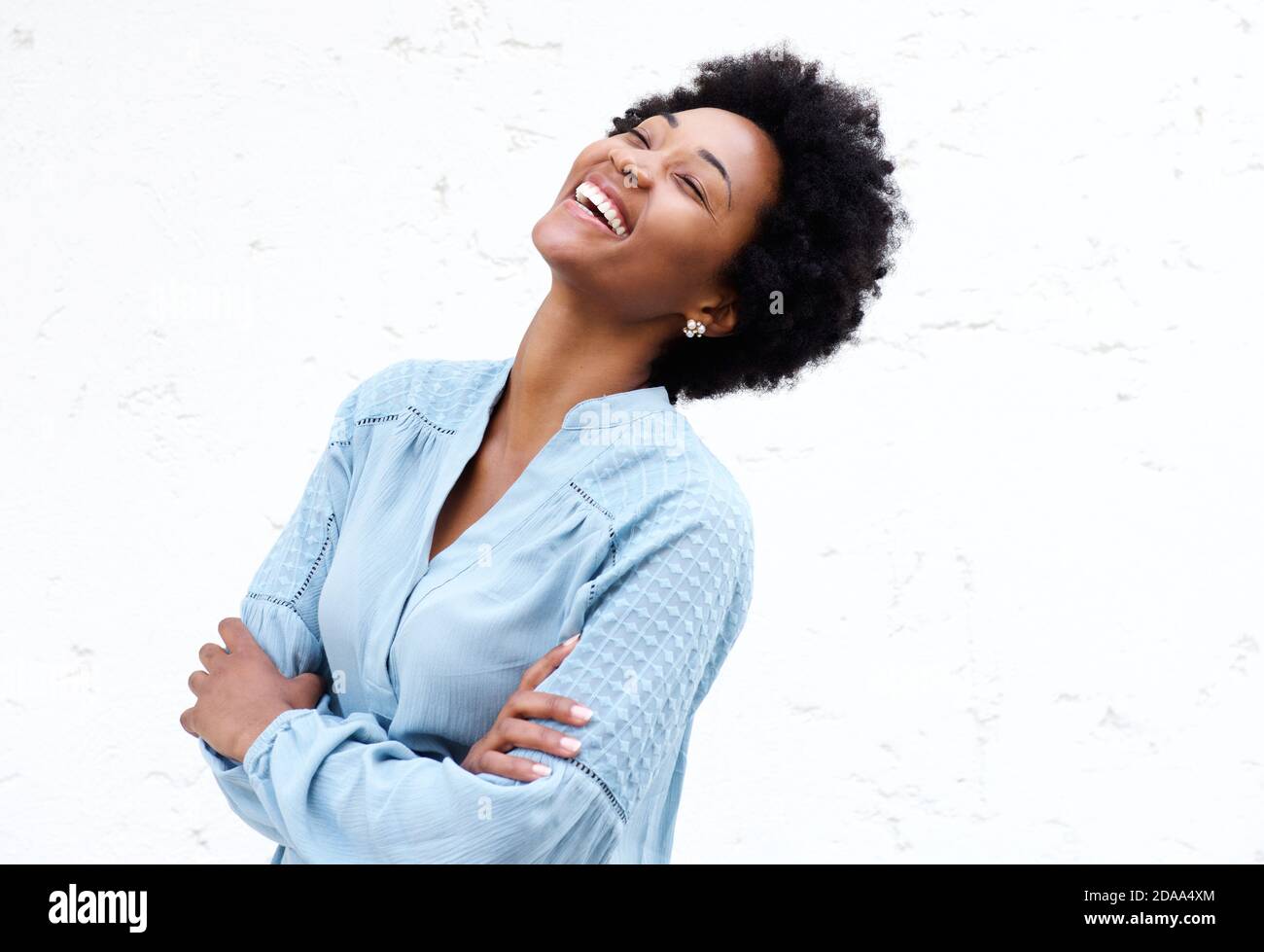 Portrait of cheerful young african woman standing with her arms crossed ...