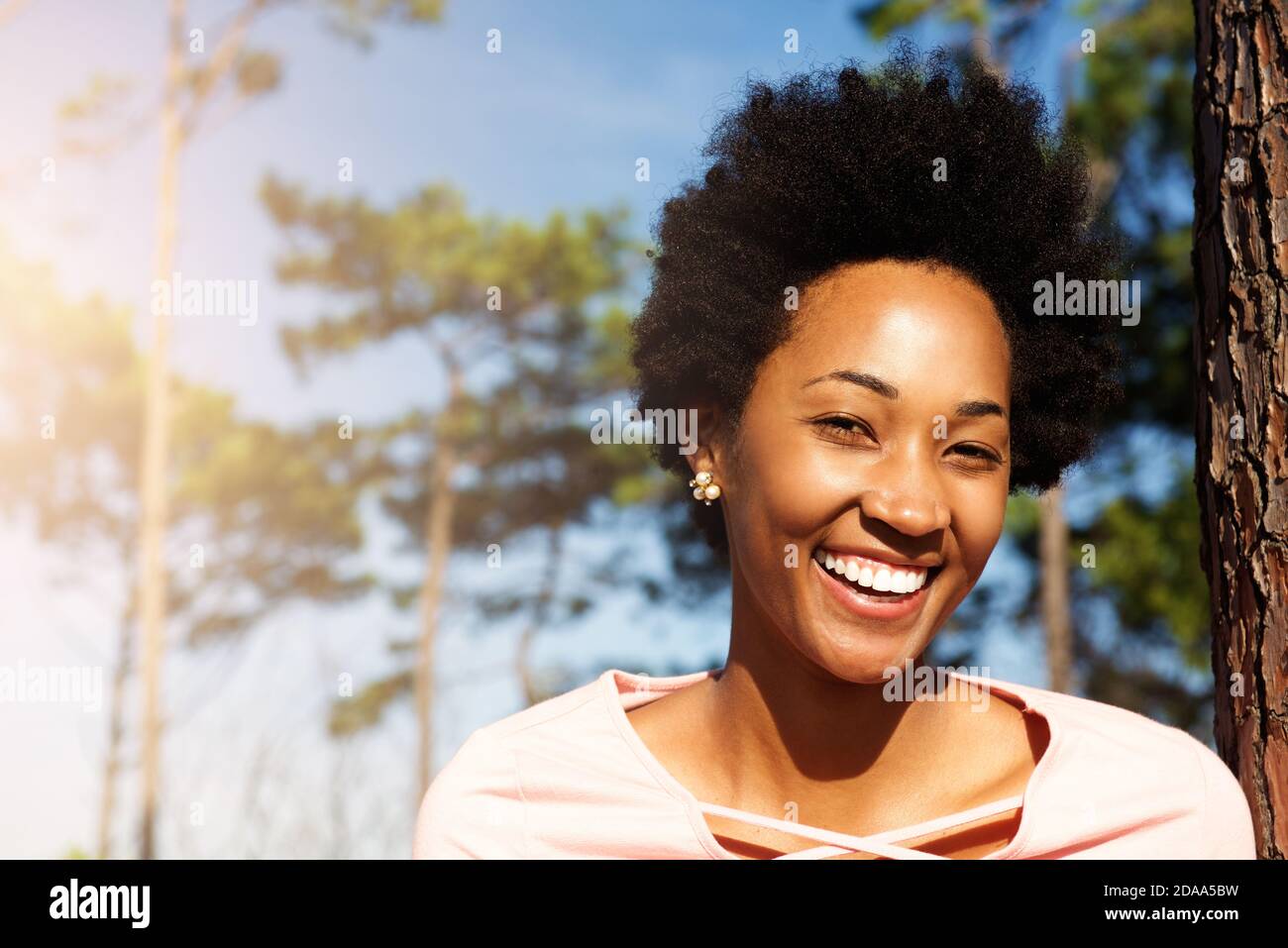 Close up portrait of happy young african woman standing outdoors and ...