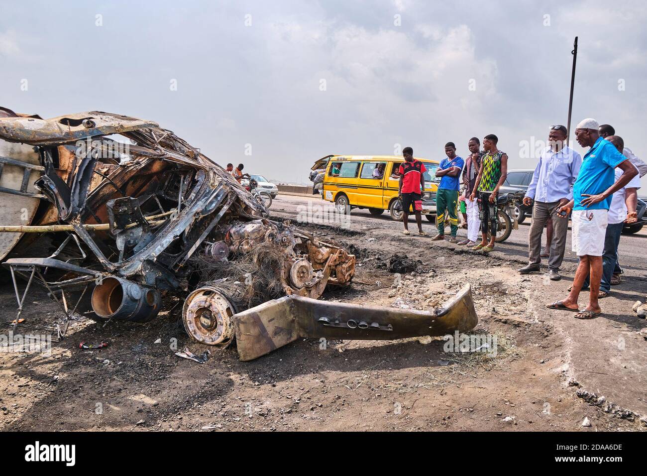 People passing by look at damaged vehicles at a site following an