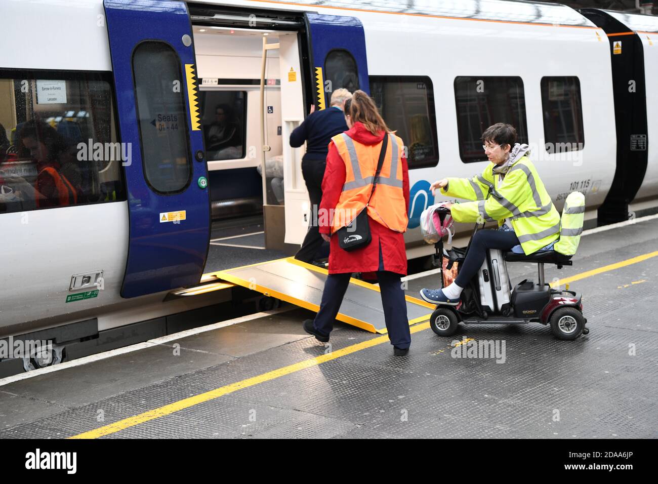 Train and station staff at Preston railway station help a disabled wheelchair user to board a