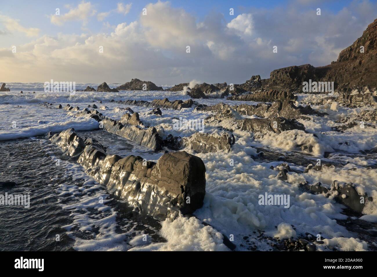 Sea Spume on the beach at Welcombe Mouth during a storm in Cornwall Stock Photo