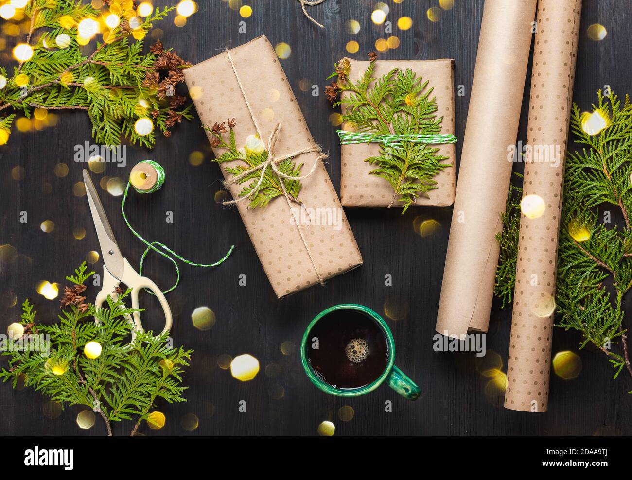 Zero waste Christmas. Wrapped Christmas gifts in craft paper with thuja branches. Beautiful Christmas lights. Top view Stock Photo