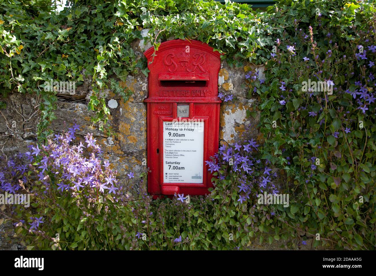 A small post box set in a stone wall in the village of Chicksgrove, near Tisbury in Wiltshire. Stock Photo