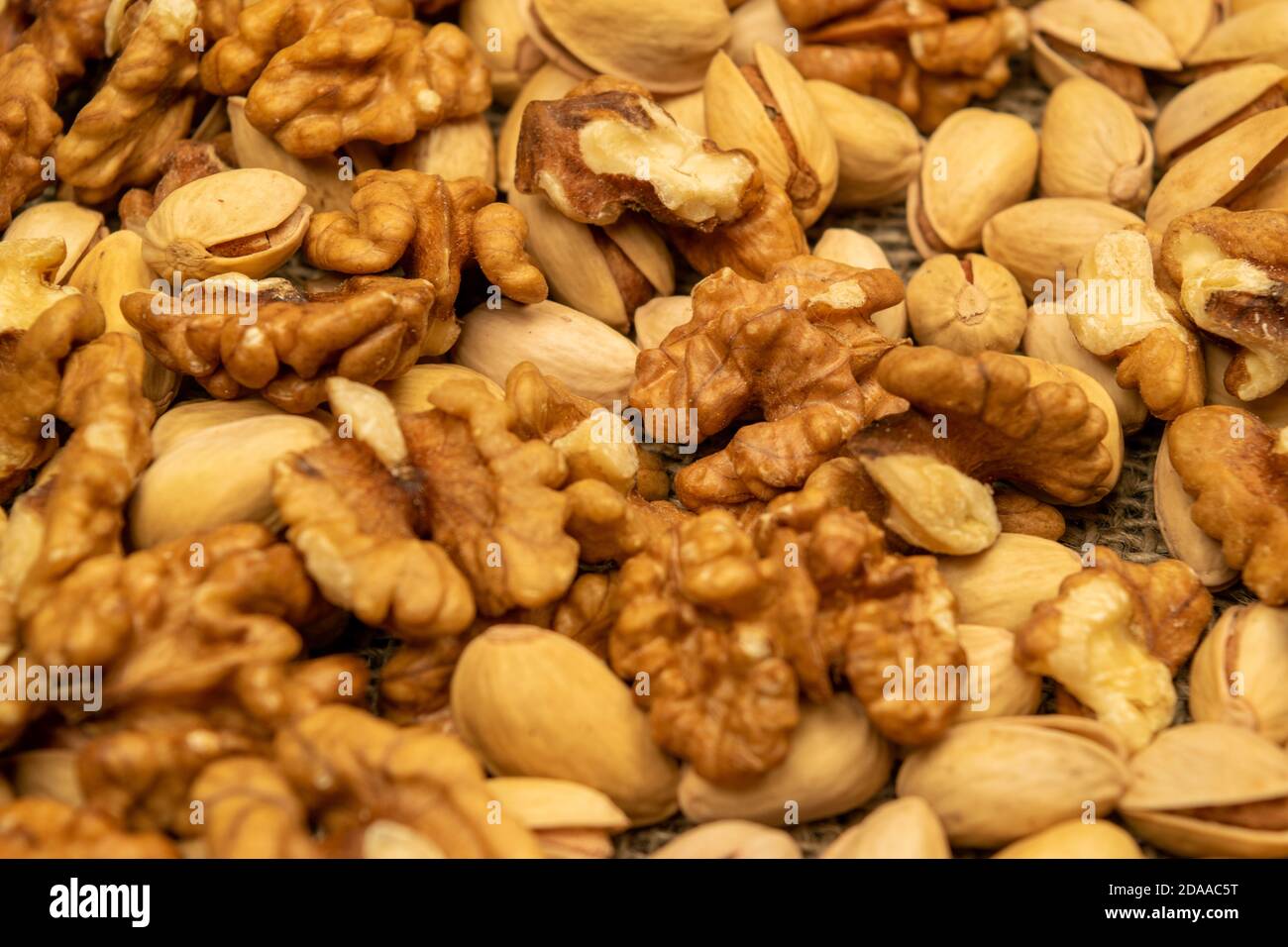 Pistachios and walnuts lie on the sacking. Close up Stock Photo
