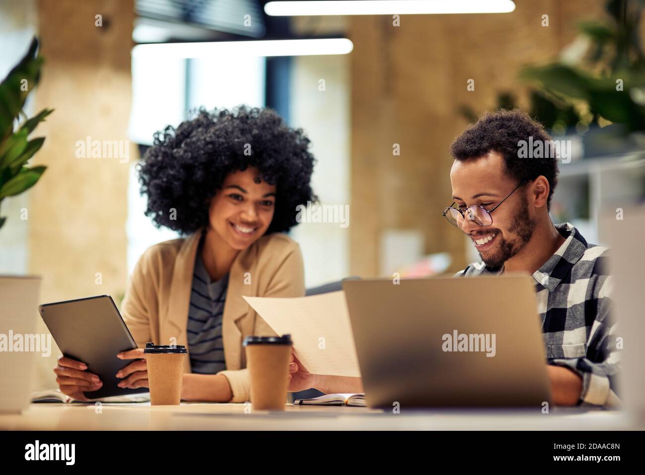 God job. Two young diverse coworkers analyzing sales report while working together in the office. Business and teamwork concept Stock Photo