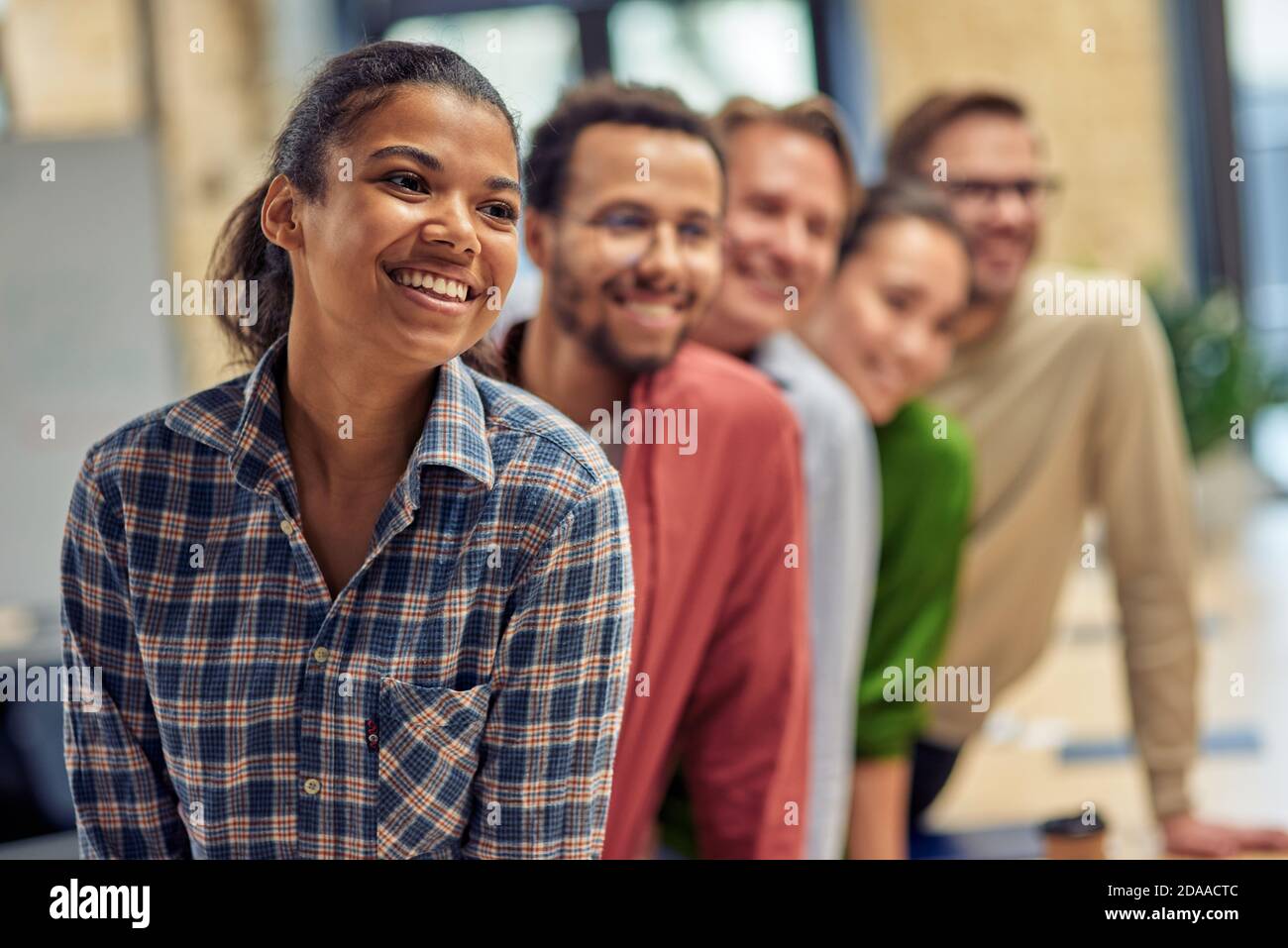 Successful startup team. Group of young happy multiethnic colleagues smiling while posing in the modern office, business people working together. Teamwork and cooperation concept Stock Photo