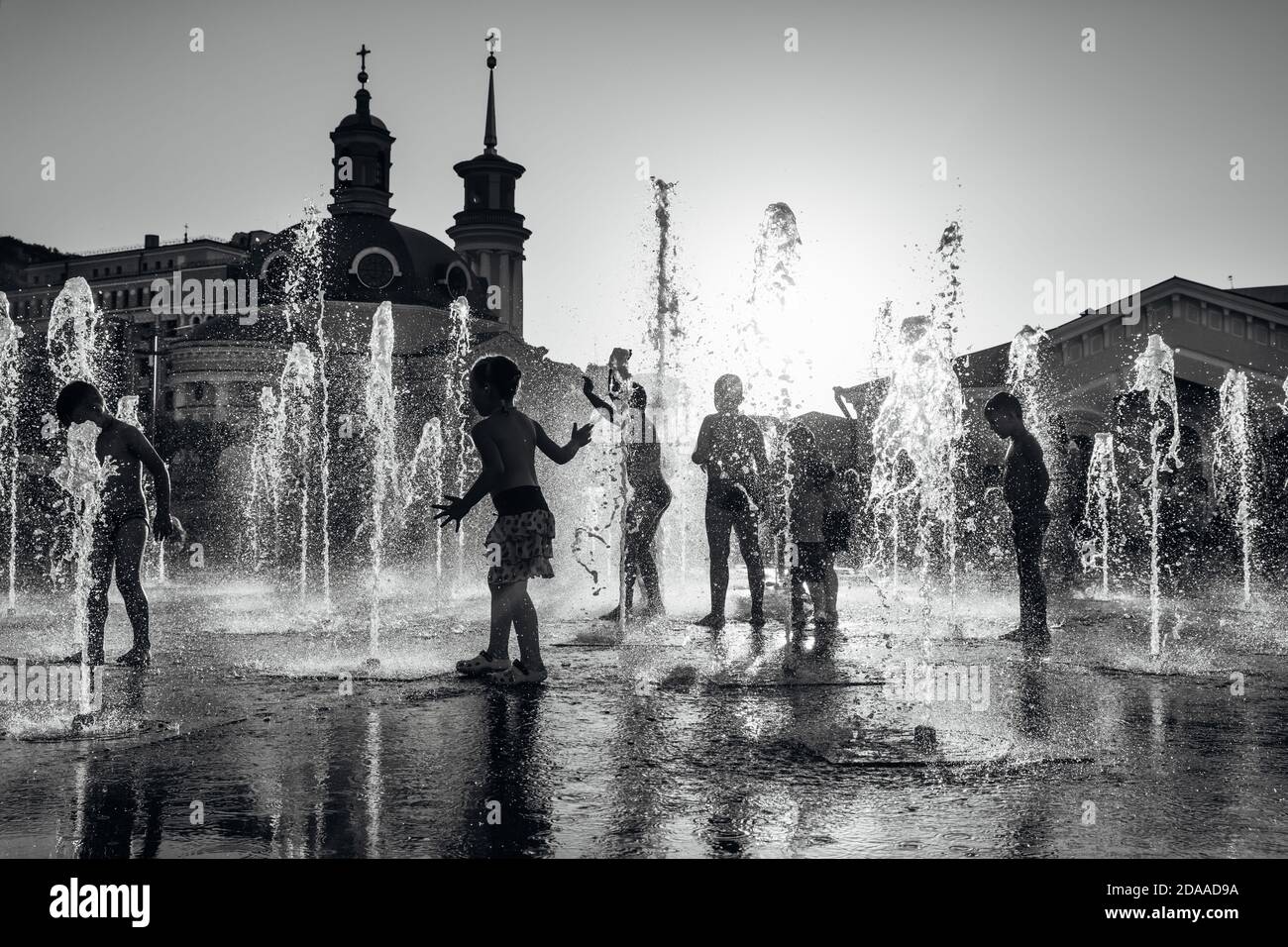 Silhouette of a group of happy children playing in a water fountain in ...