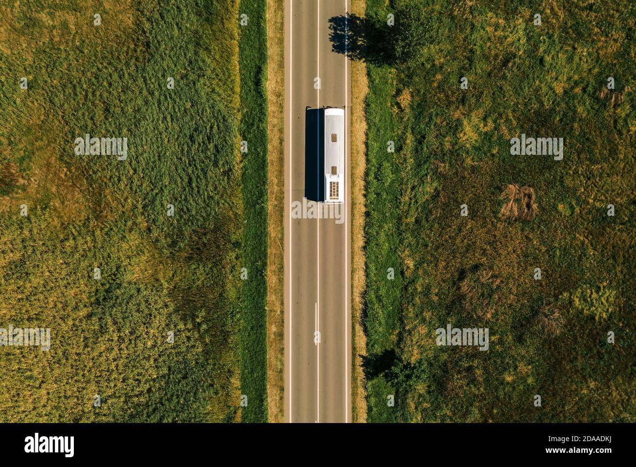 Aerial view of passenger bus on road through countryside, top view from drone pov Stock Photo