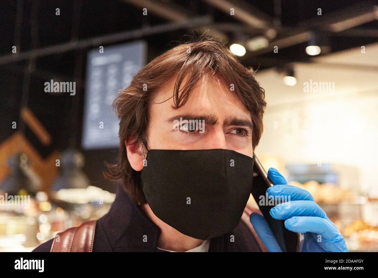 Customer with face mask due to Covid-19 pandemic with smartphone while shopping Stock Photo