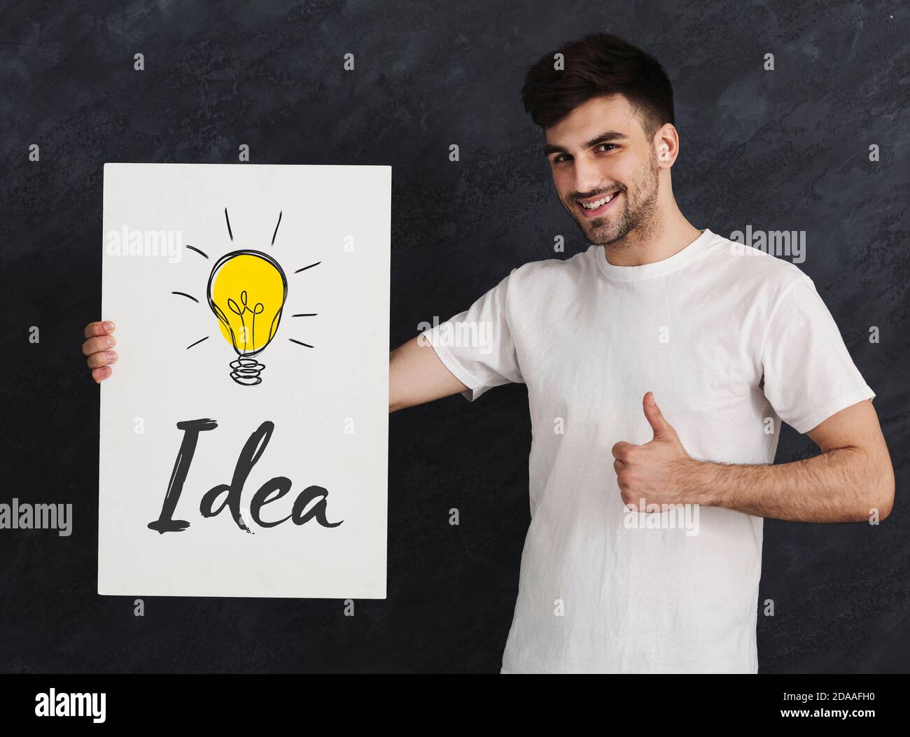 Happy Millennial Guy Showing Thumbs Up And Holding Poster With Word