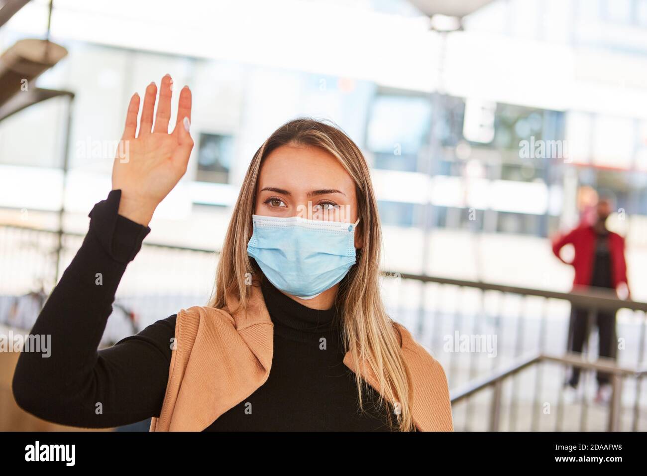 Woman waving as a passer-by with face mask because of Covid-19 pandemic in the city Stock Photo