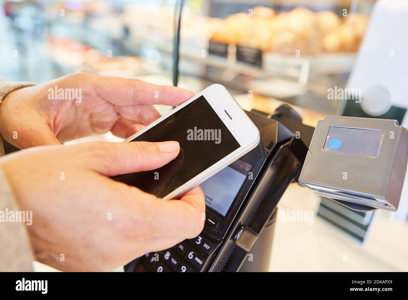 Hands hold smartphone with app for contactless payment at the supermarket checkout Stock Photo