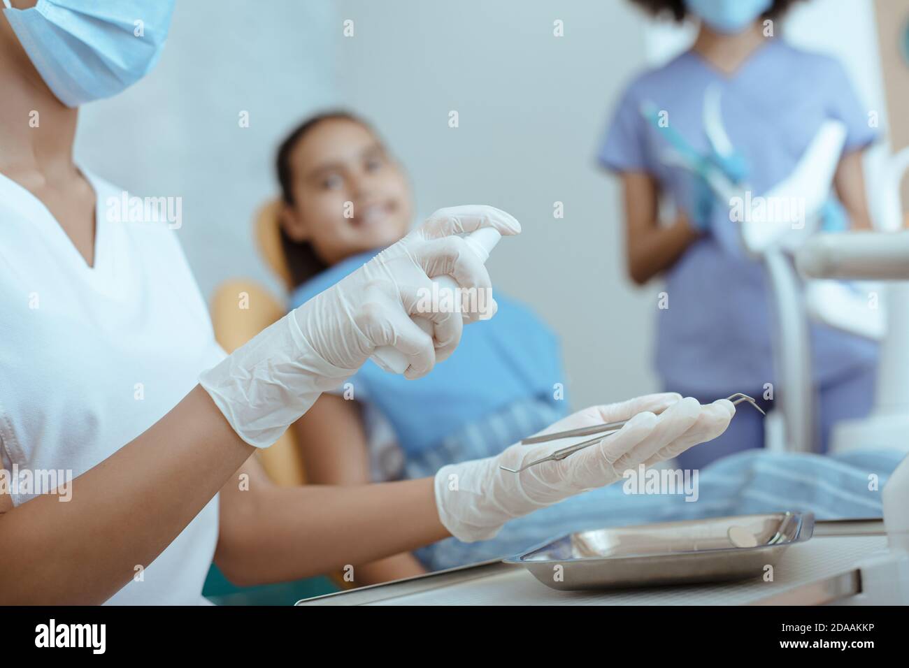 Millennial woman doctor in rubber gloves and protective mask processes dental instruments Stock Photo