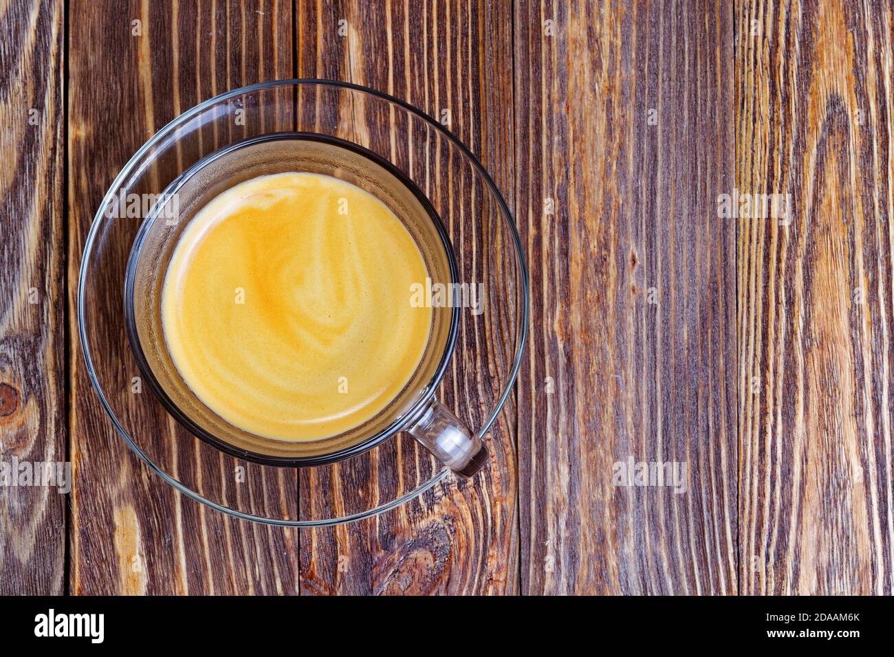 Transparent glass cup with espresso on wooden table. Top view. Stock Photo