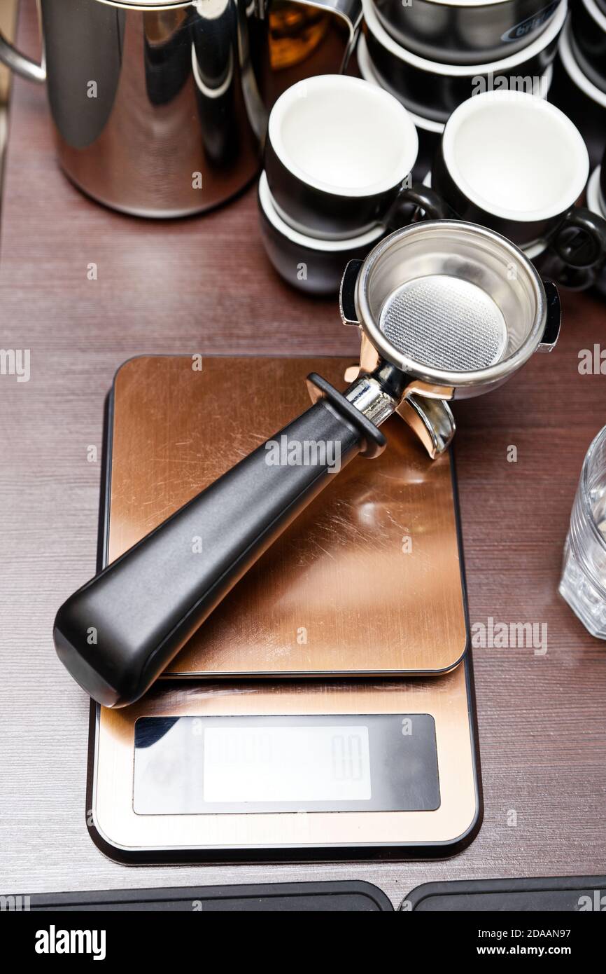 Clean empty portafilter for coffee maker lies on the scales. Barista
