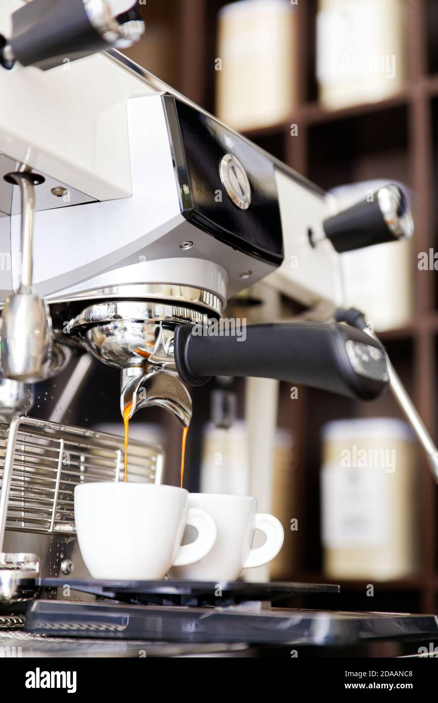 Coffee brewing in coffee machine. Espresso pouring in two white cups. Shallow focus Stock Photo