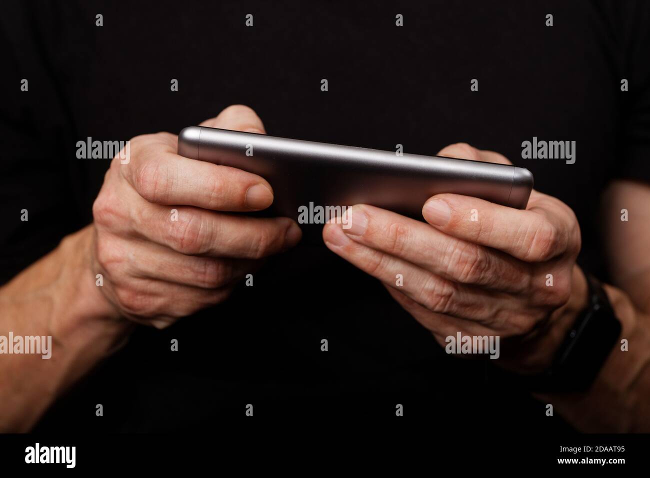Closeup mans hand using smartphone on black background. Shallow focus. Stock Photo
