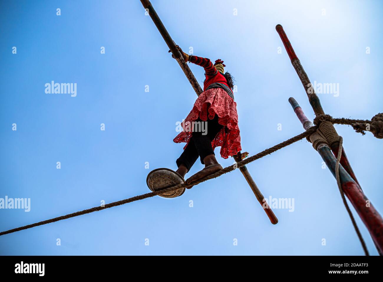 an indian girl performs street acrobatics by walking on the tight rope at pushkar camel festival. Stock Photo