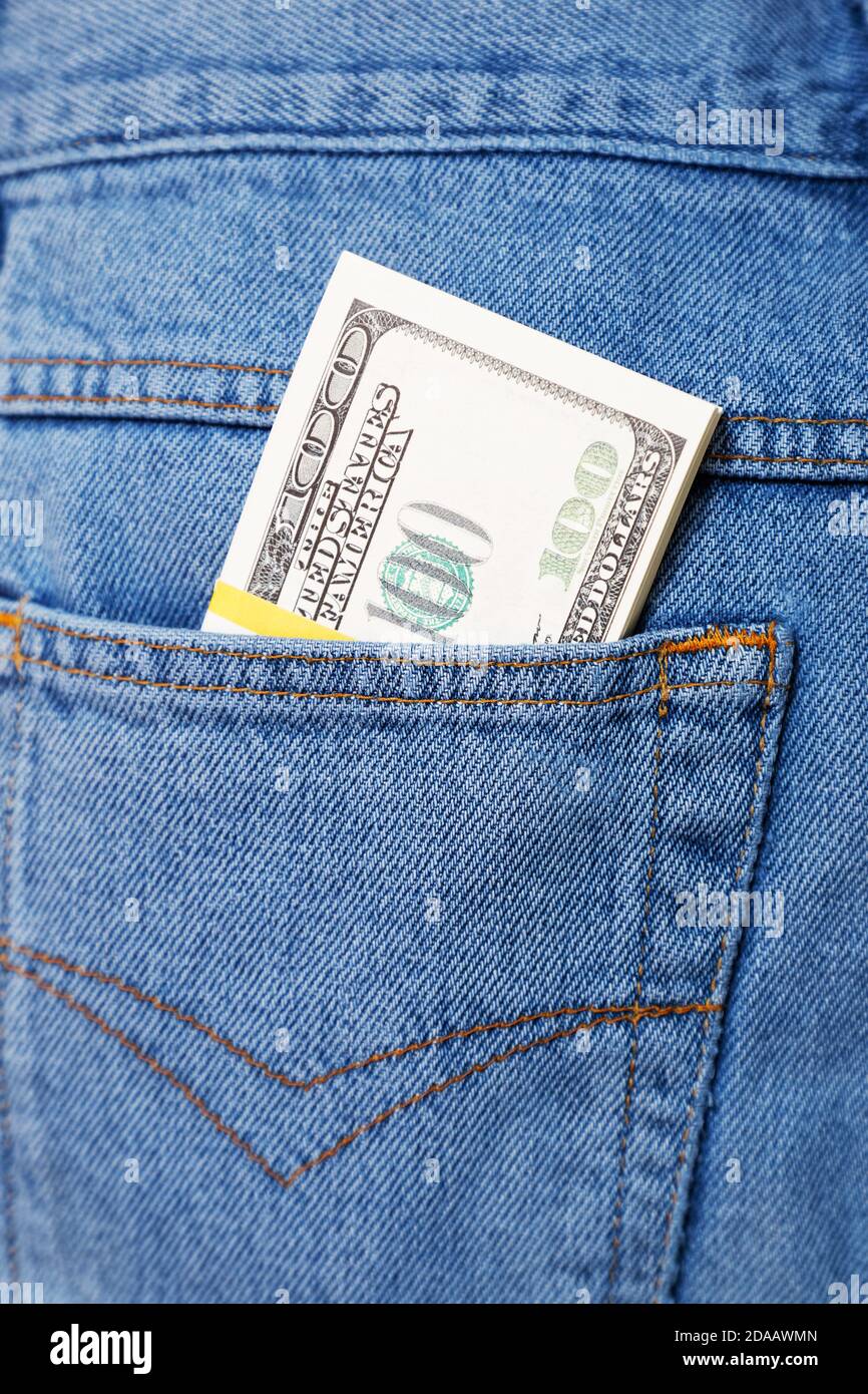 Closeup bundle of 100 dollar bills sticking out of a blue jeans pocket Stock Photo