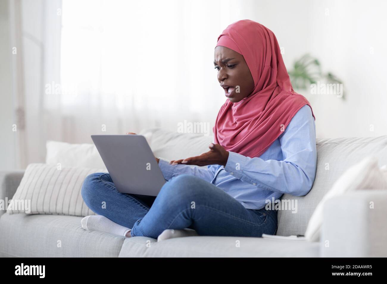 Computer problems. Angry arab woman having issues with laptop at home, annoyed of bad internet connection, free space Stock Photo