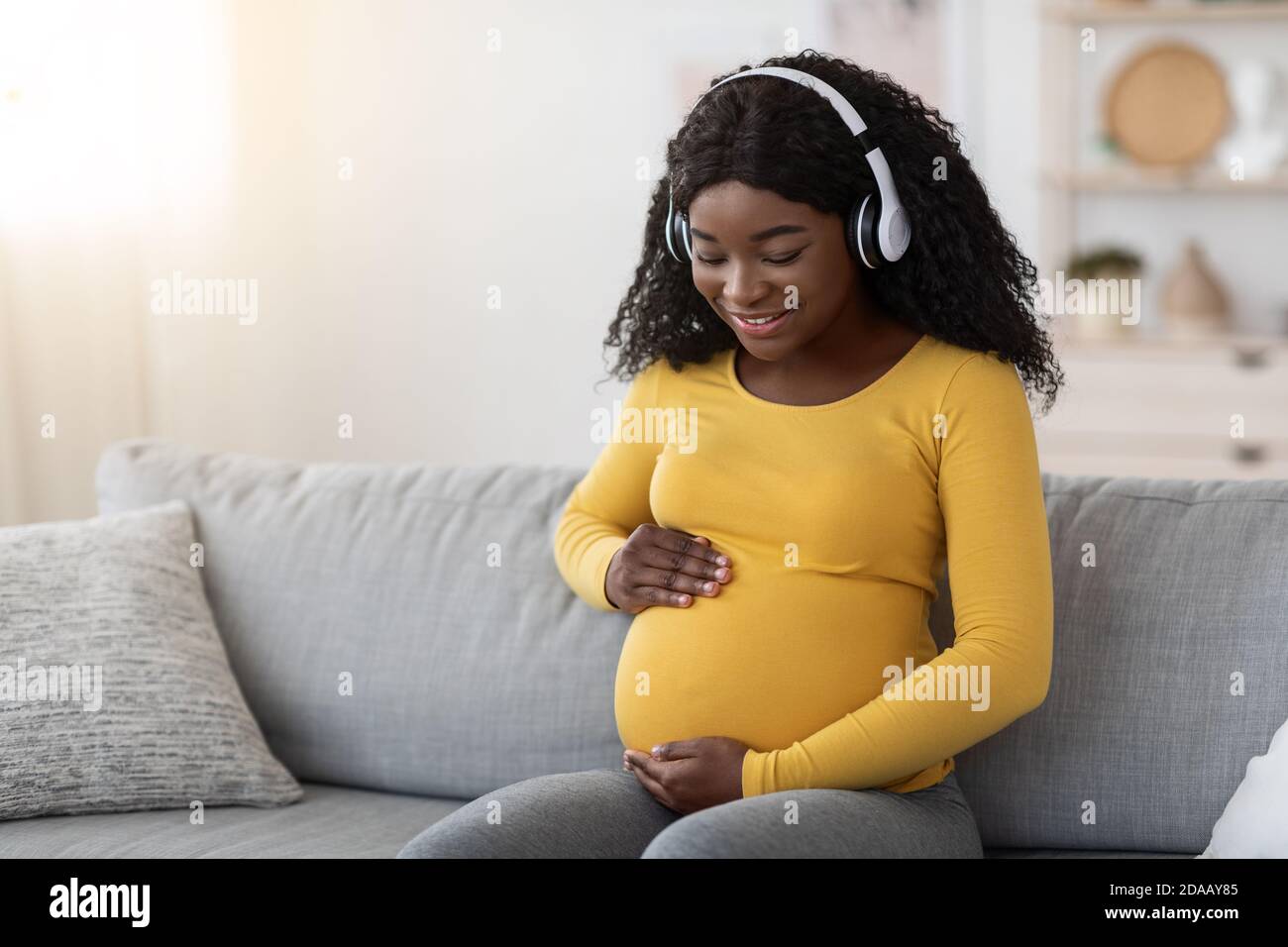 Happy pregnant black woman listening to music in headphones Stock Photo ...