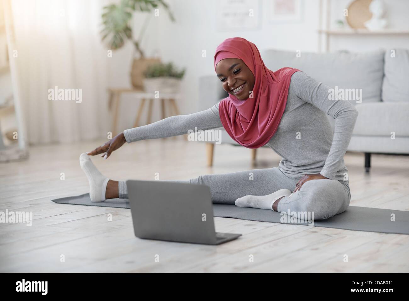 Black muslim woman in hijab exercising in front of laptop at home Stock ...