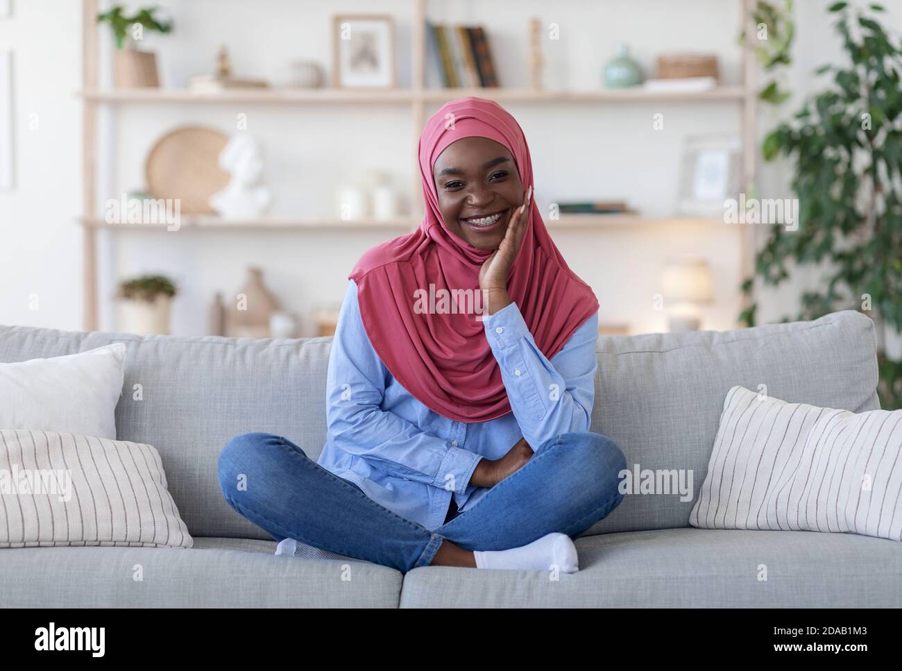 Traditional Black Muslim Woman In Hijab Posing On Couch At Home Stock ...