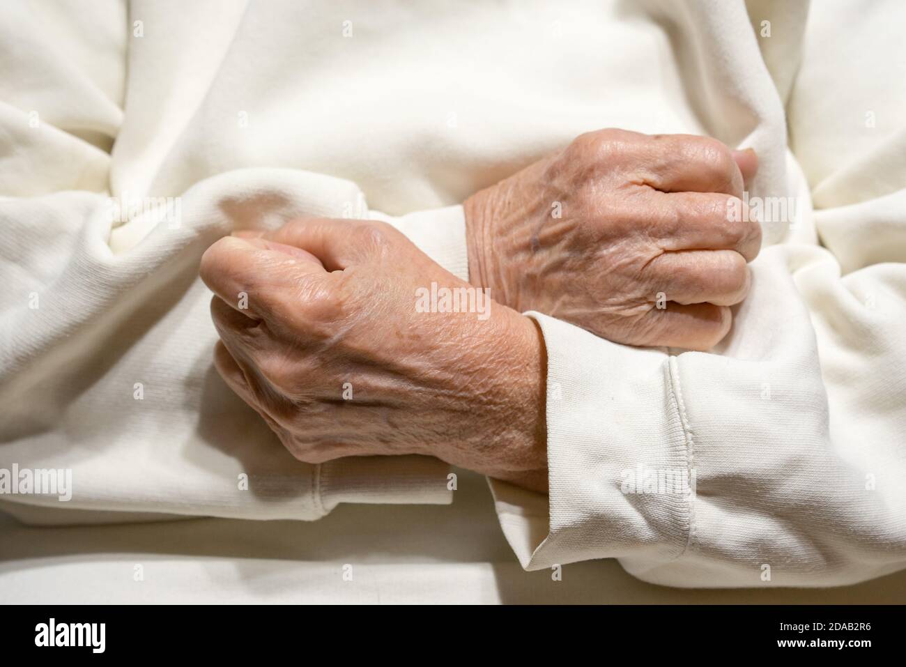 Hands of an elderly woman clenched in fists on her chest. Stock Photo