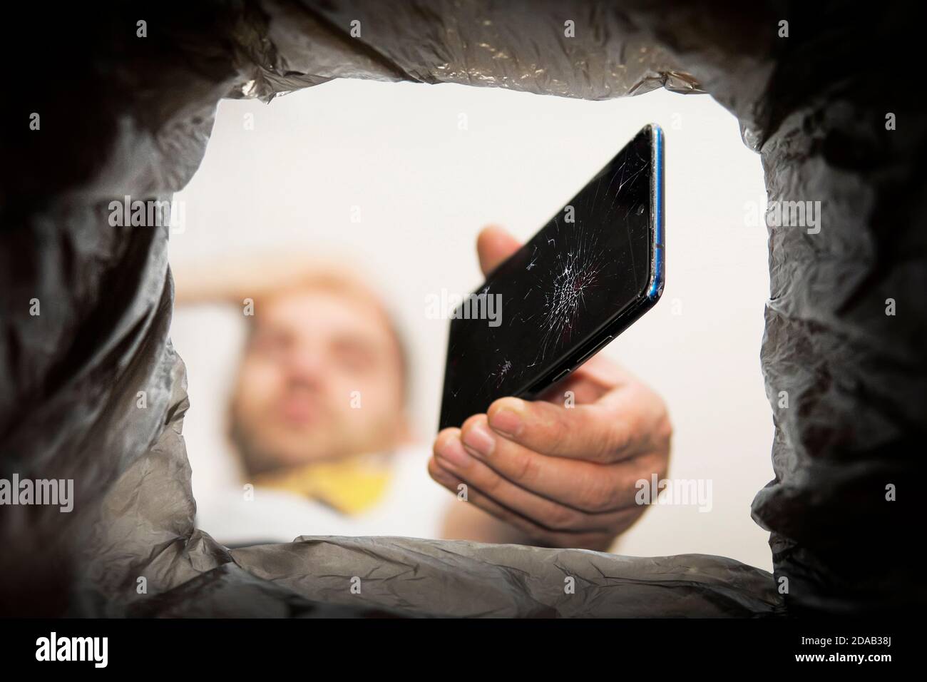 Young man throwing smartphone in litter bin outdoors. Recycling a