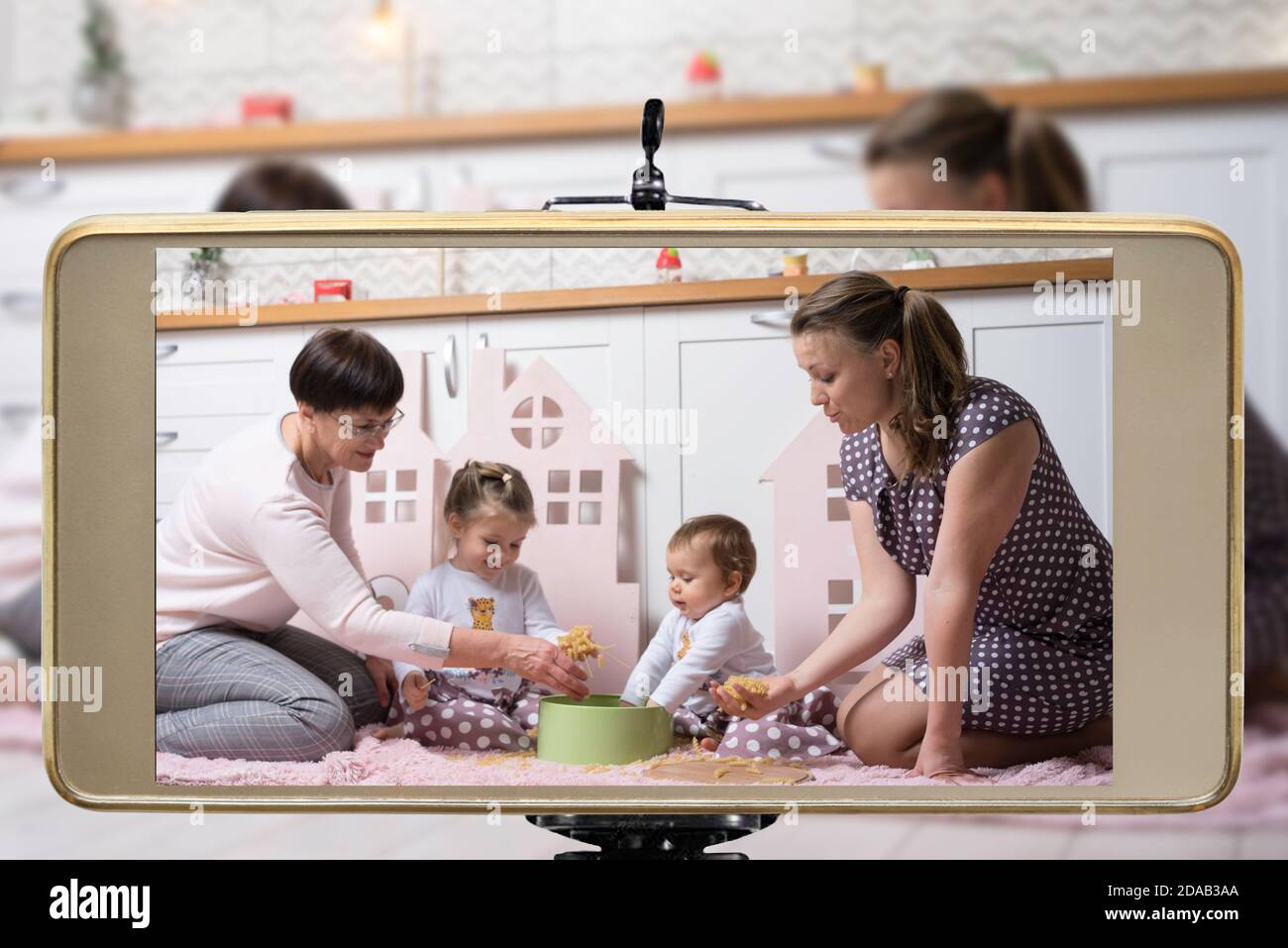 Young female blogger online influencer mom with grandmother and two daughters, live streaming a parent playing with children show on social media usin Stock Photo